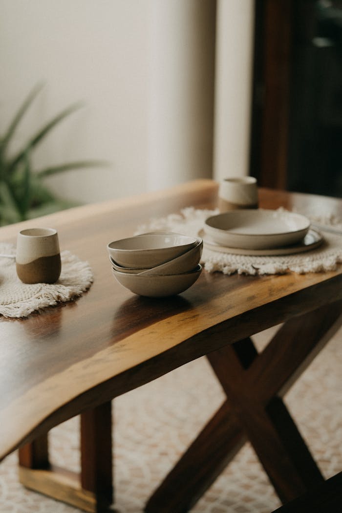 services-03 Rustic dining setting with ceramic bowls, cups, and plates on a wooden table, creating a cozy ambiance.