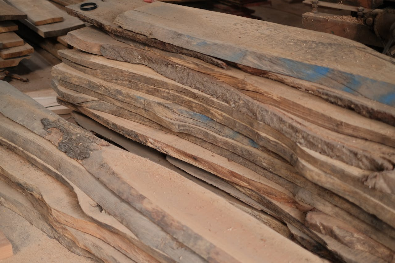 services-02 Stack of wooden planks in a workshop setting, ideal for woodworking projects.