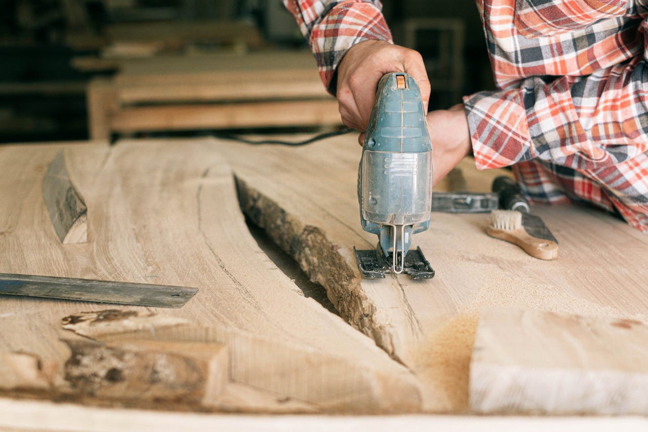 who-we-are Close-up of a carpenter cutting a wooden plank with a power tool in a workshop.